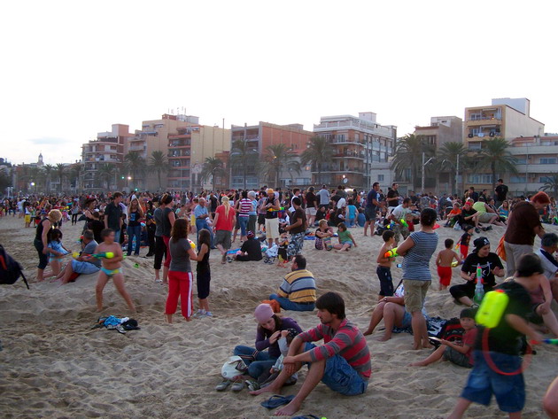 large group of people on the beach playing with kites