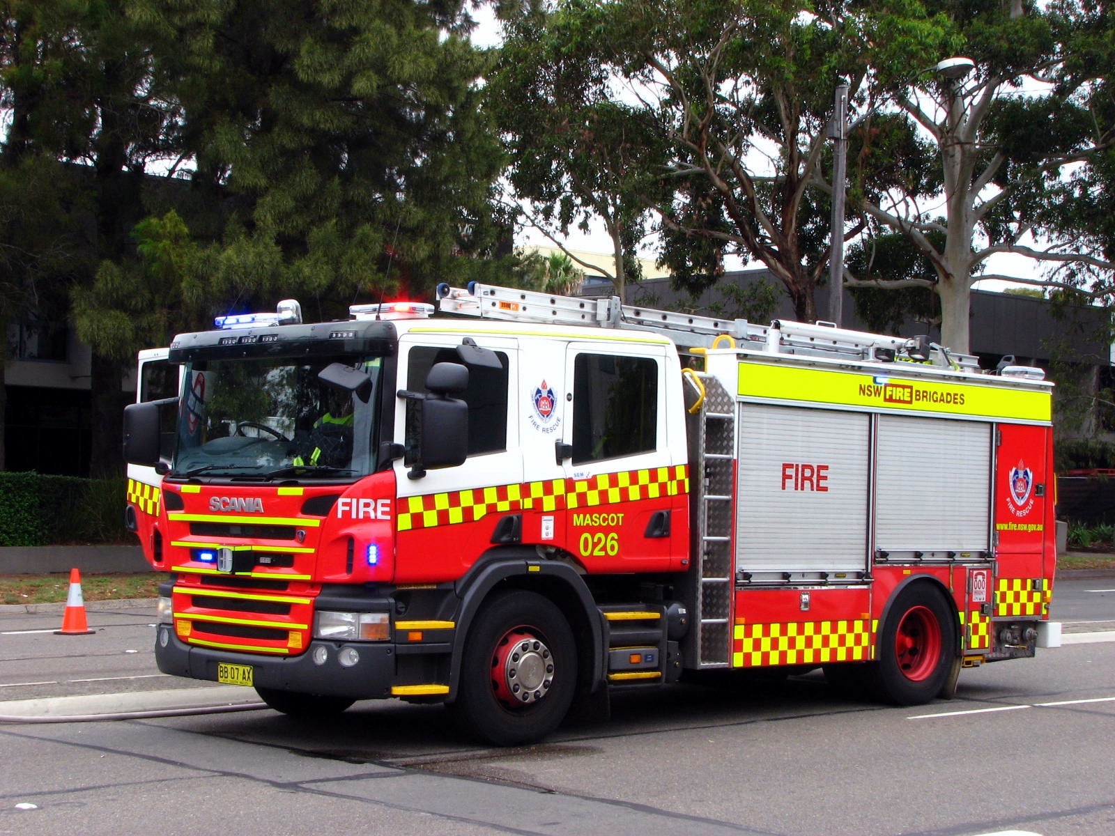 fire truck driving through an intersection with trees in the background