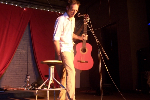 a man is standing by the guitar, on stage