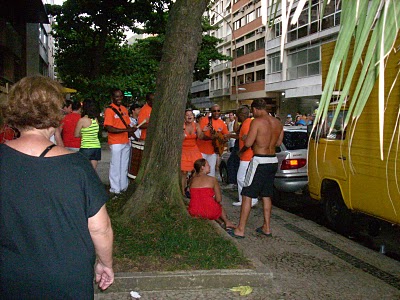 group of people in orange vests standing on the sidewalk next to trees