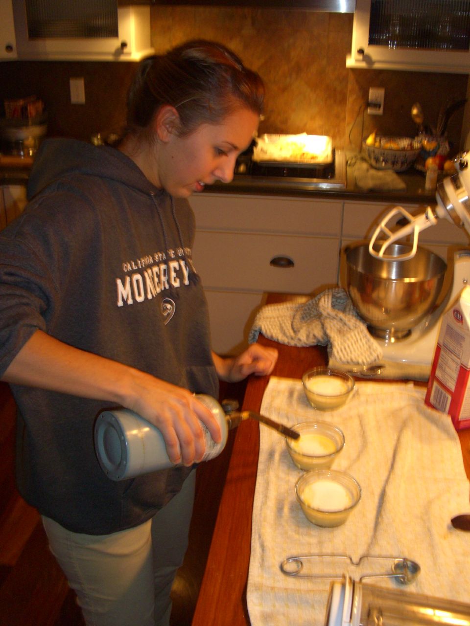 a woman pouring ingredients into a cup for making cupcakes