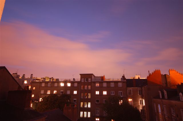 an overcast evening with the view of some buildings and lit up windows