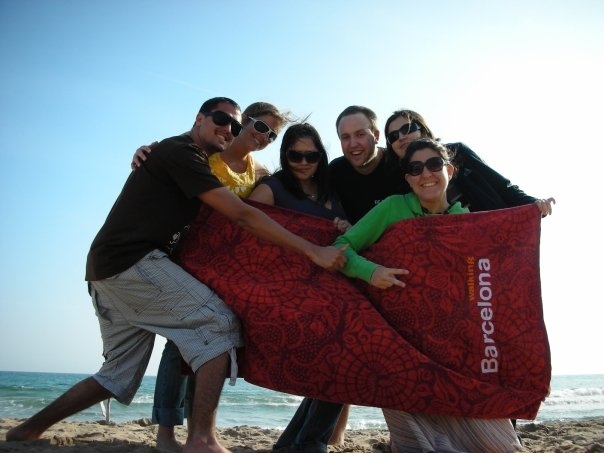 a group of friends standing next to each other with a beach towel