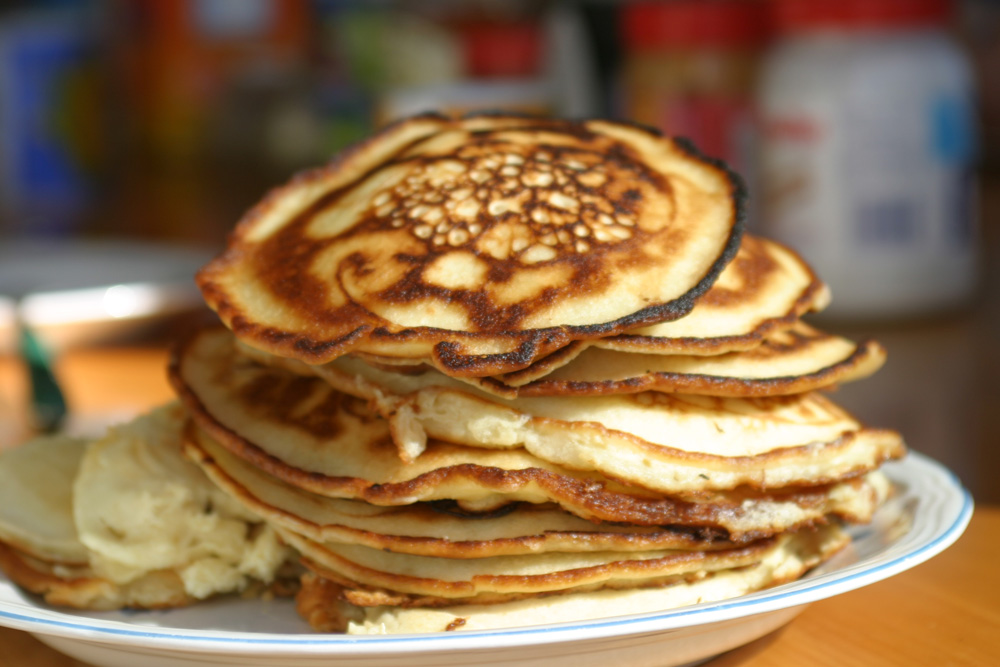 pancake stack on white plate on wood table