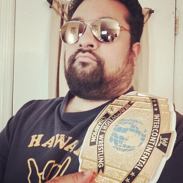 a man in sunglasses, holding a golden wrestling ring