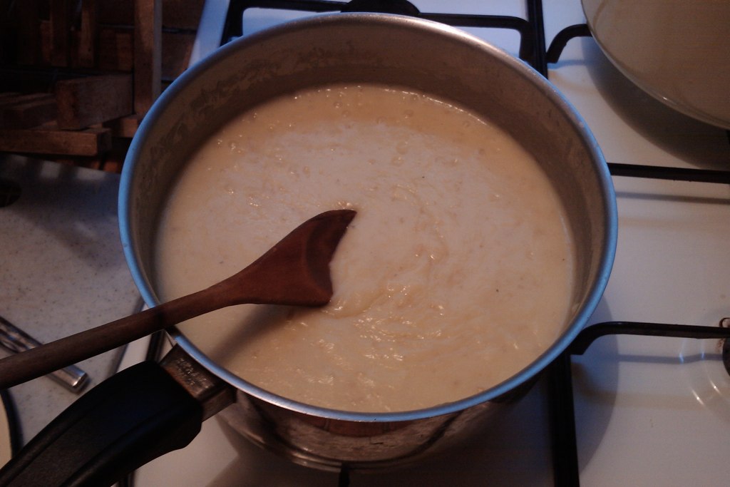 a pot is full of soup, which is in a pan with a wooden spoon