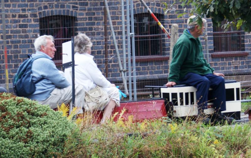 two people and a woman sit on a bench outside a building