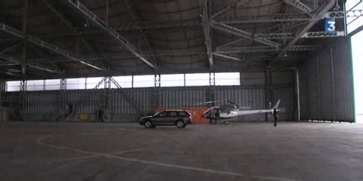 a small car in a large garage under a plane