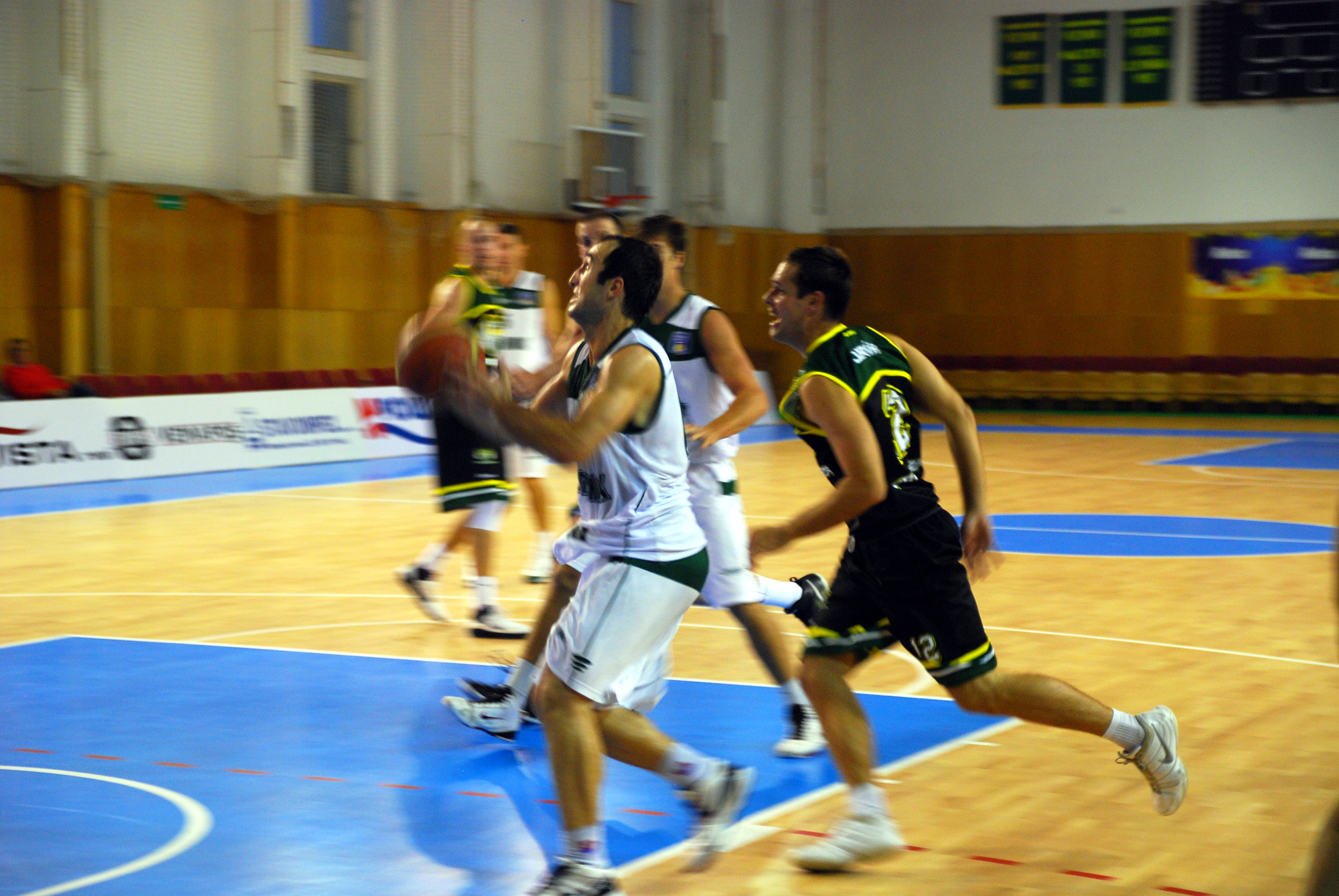 men are playing basketball while onlookers look on