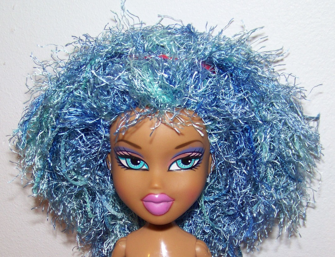 a blue and green doll with a very large afro