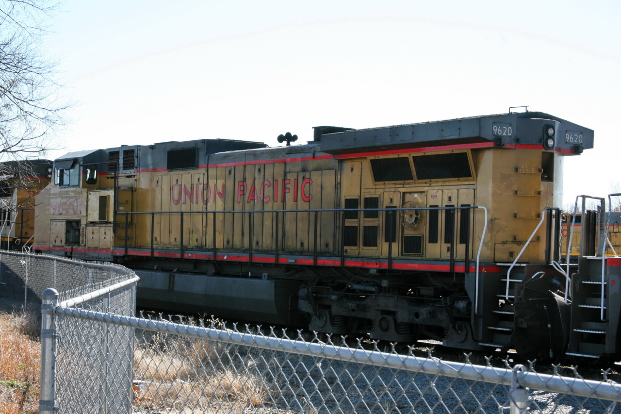 a black and yellow train engine pulling carts down the tracks