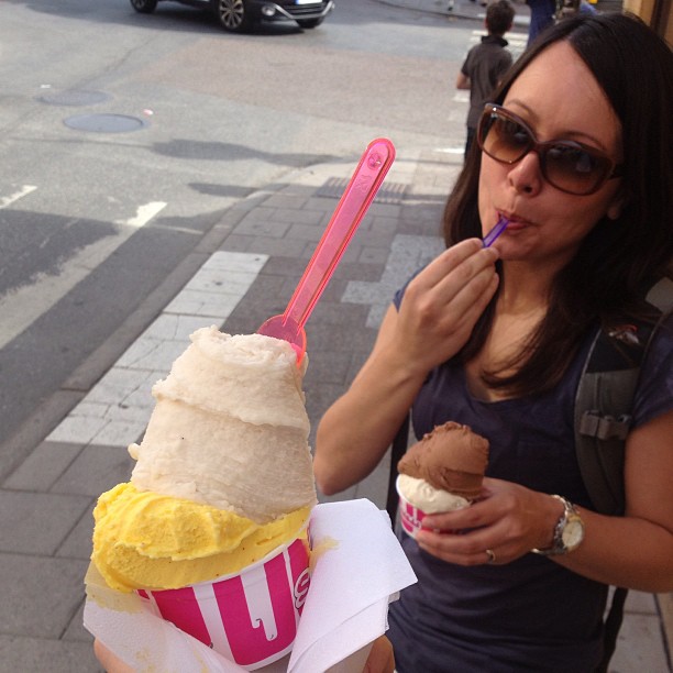 a lady is eating an ice cream sundae with her phone