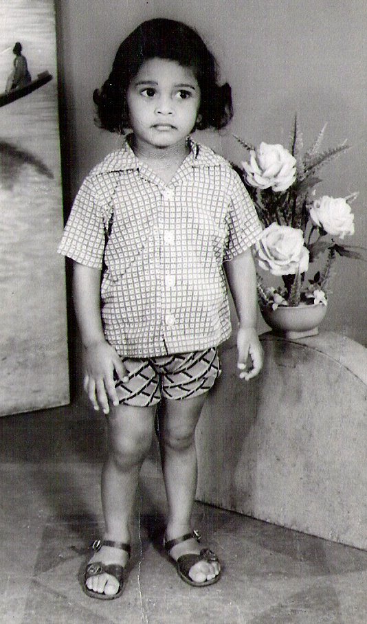 a  in a shirt and shorts, standing beside some flowers