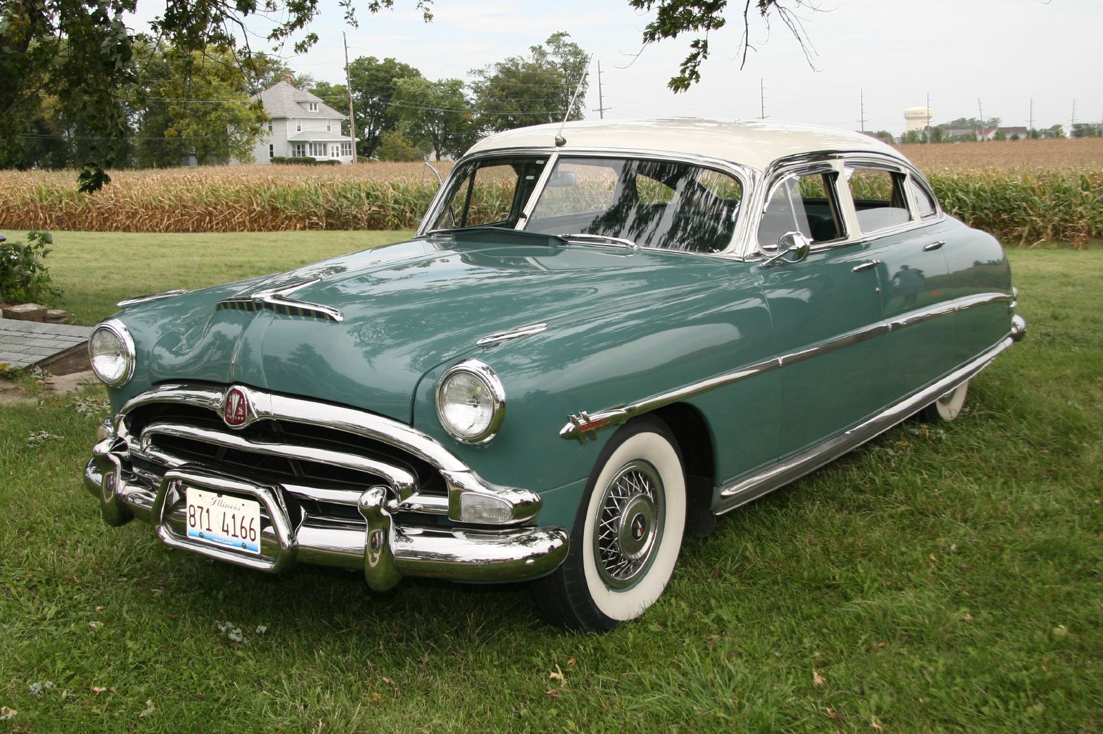 an old green car parked in the grass