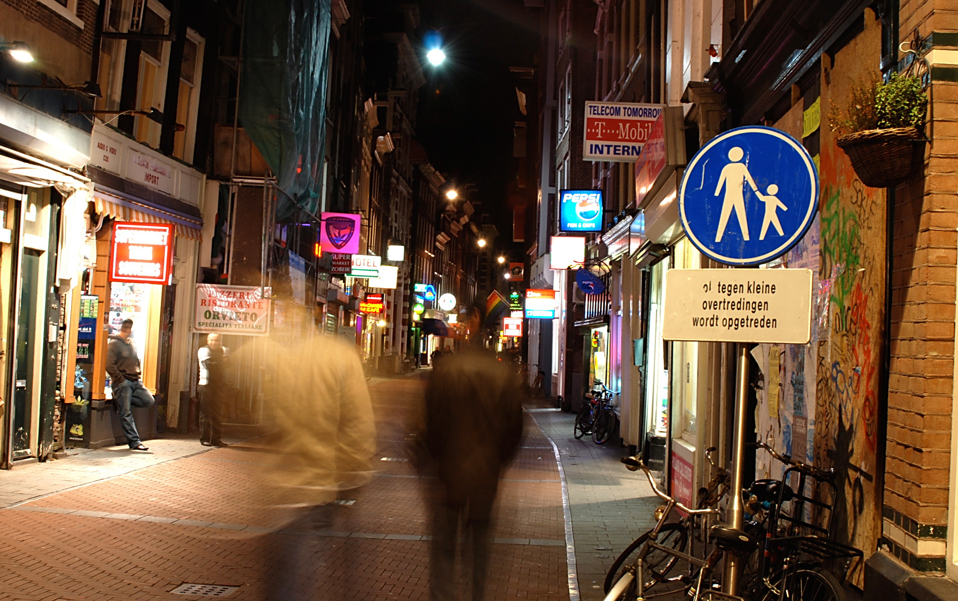 people walk down a city street at night