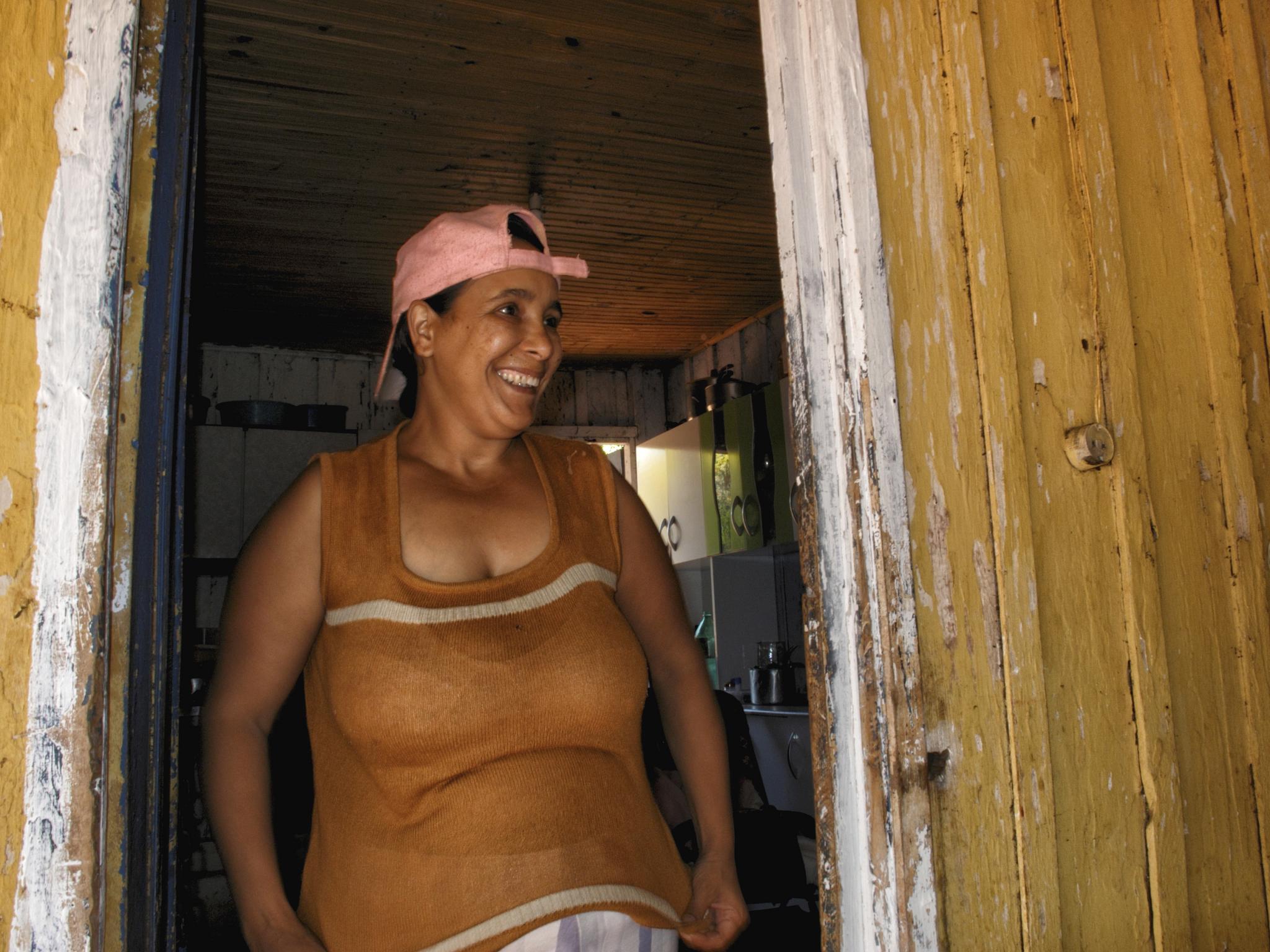 a lady wearing a pink hat is smiling as she comes out the door