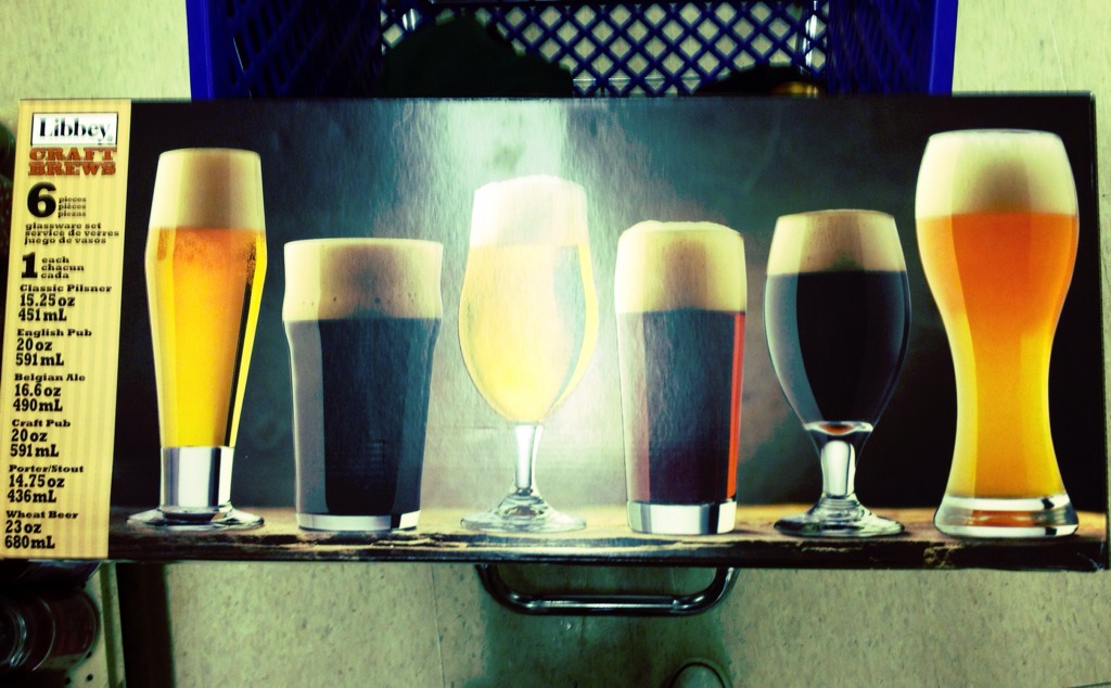 a row of five different colored glasses with ale