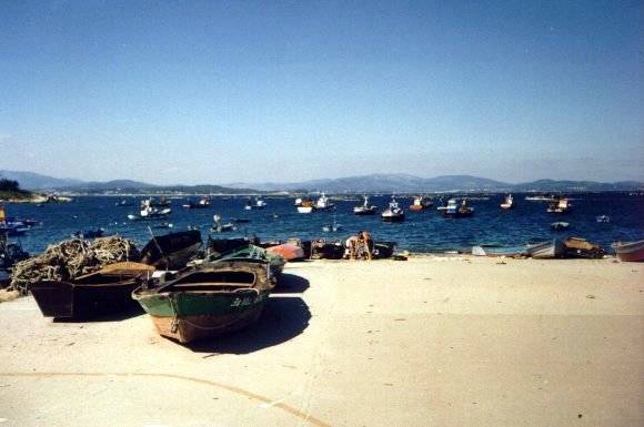boats and other objects on the beach next to a body of water