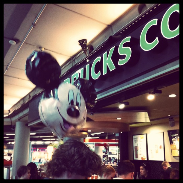 a mickey mouse balloon hangs over a crowd of people