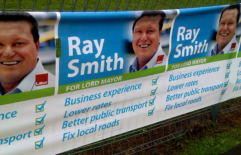 three political campaign banners on a wire fence
