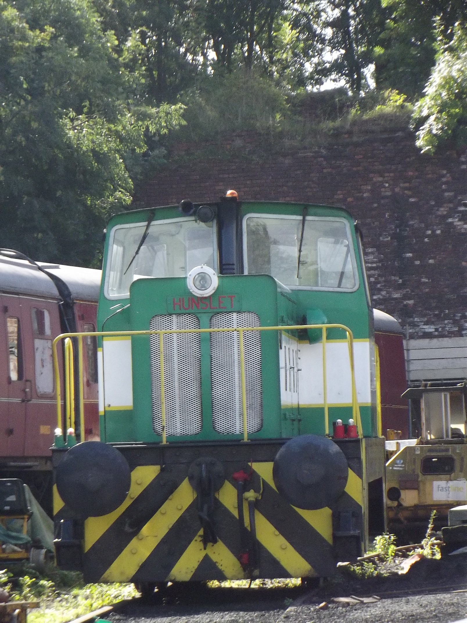 a green train engine in the middle of some tracks