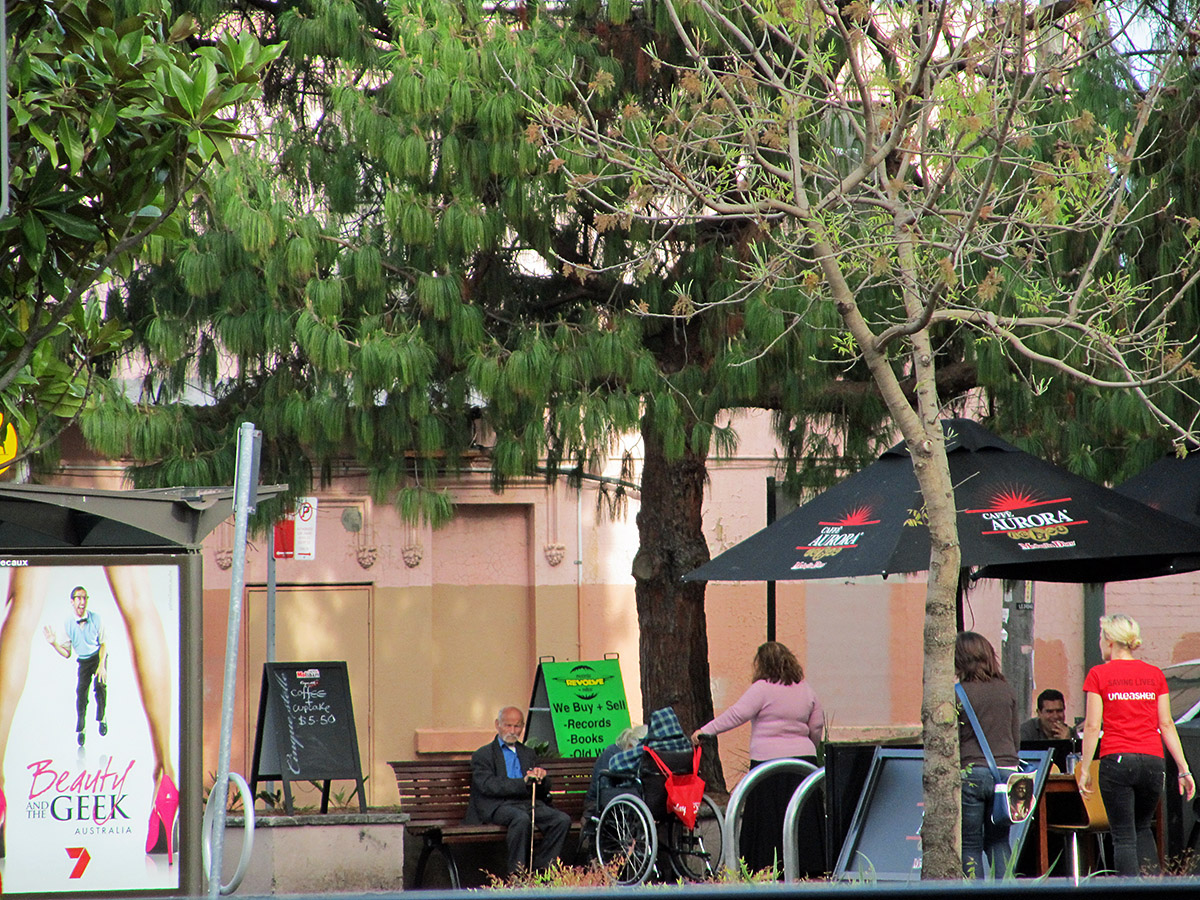 several people sitting under umbrellas under the shade of trees