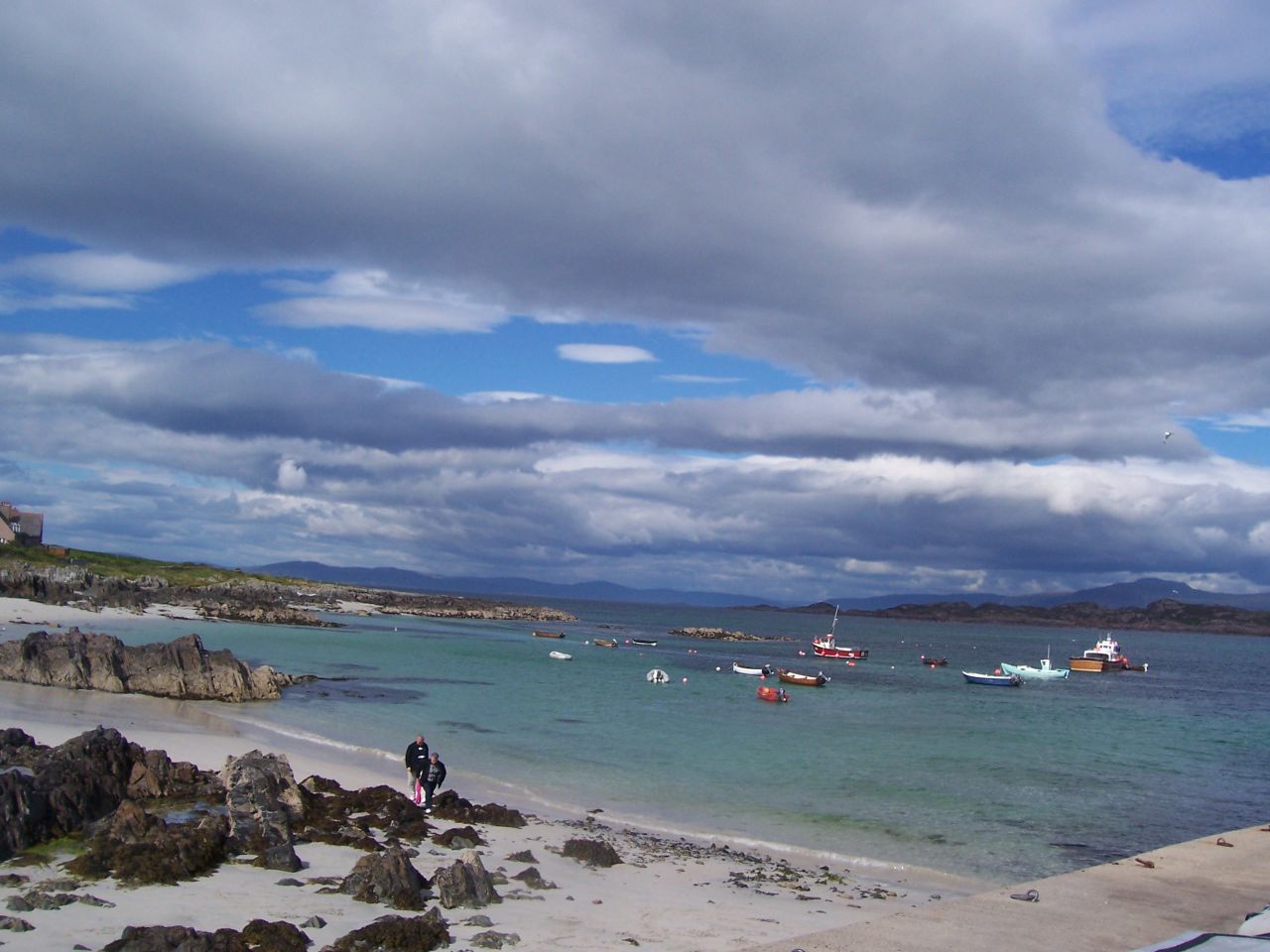 people standing on the shore watching boats out in the water