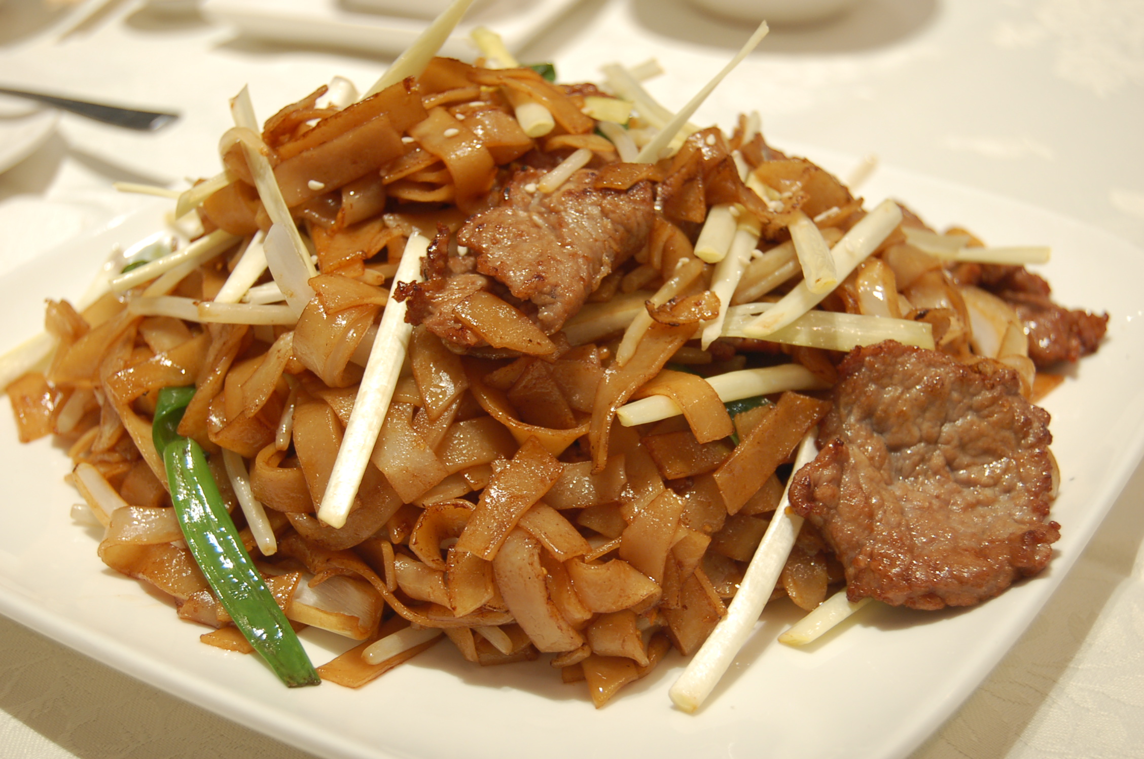 food is served on a white plate topped with meat and grated onions