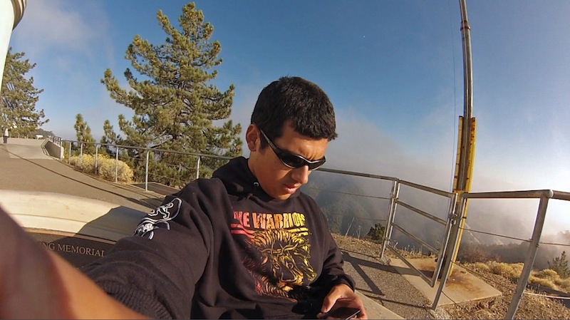 a man sitting on the side of a wooden bench