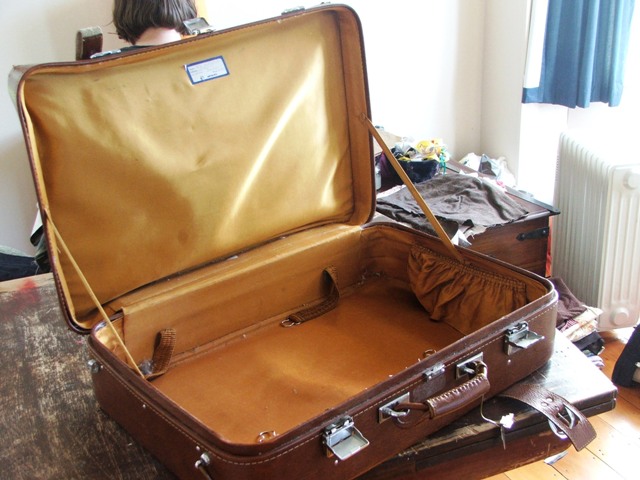 the suitcase on the wooden floor has a strap on it