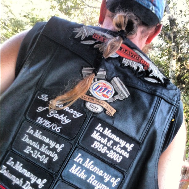 a woman in a black leather vest and several patches