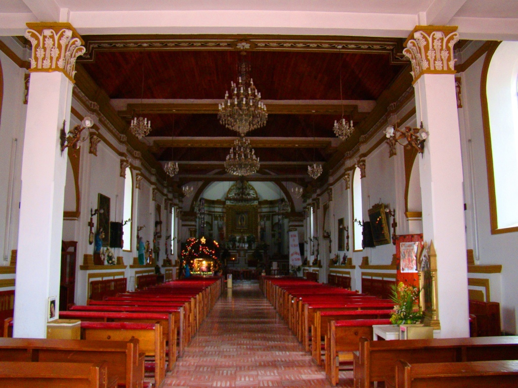 a long empty church with red and gold pews