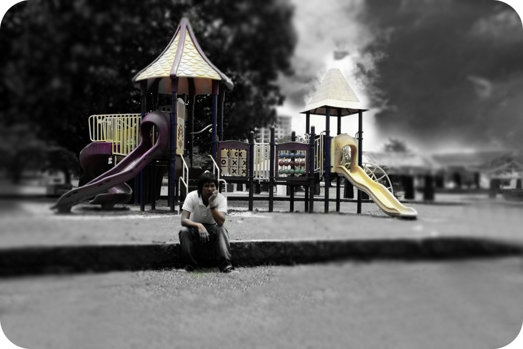 a man sitting under a rain umbrella next to a park