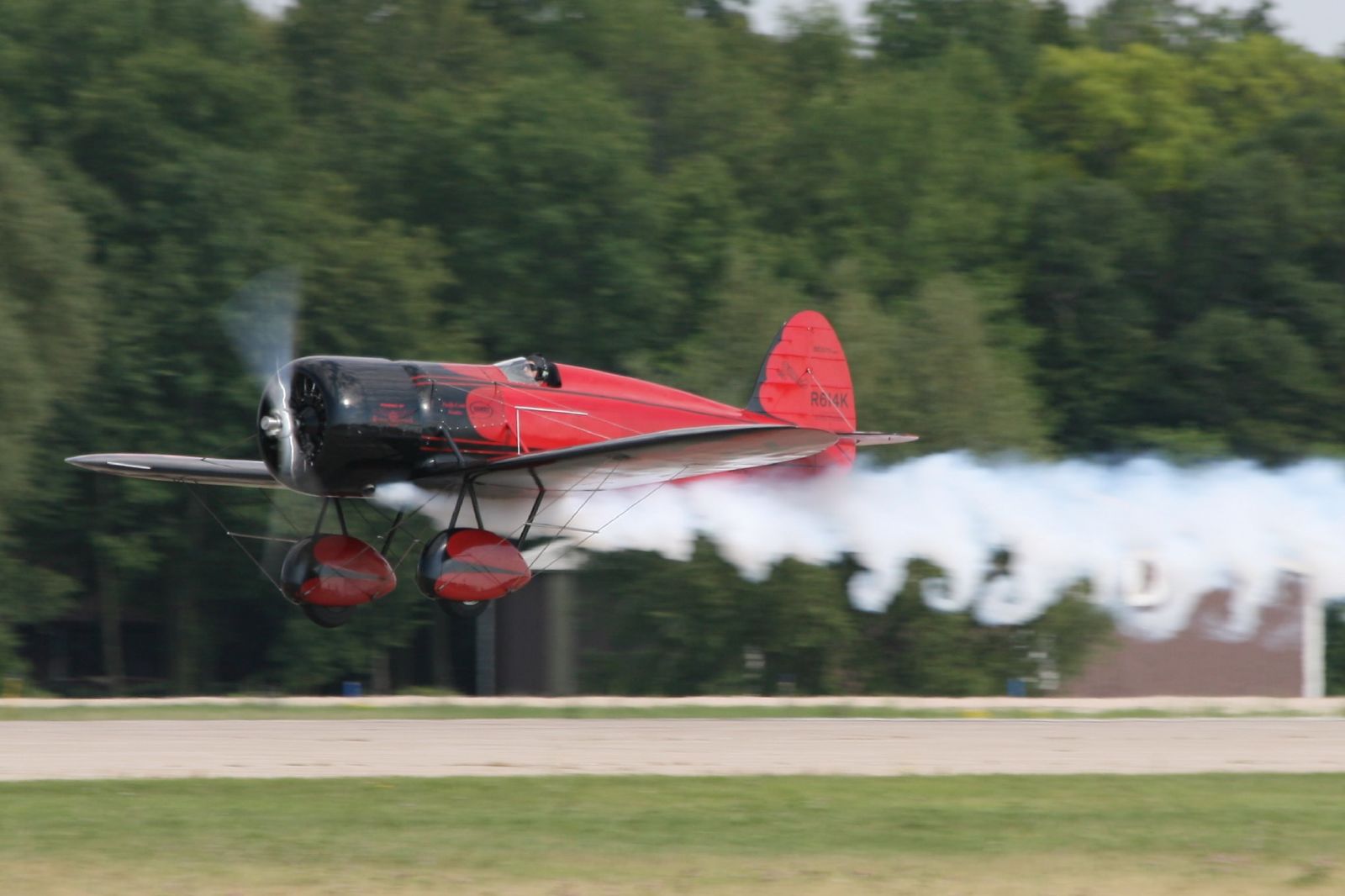 a small red plane taking off from the runway