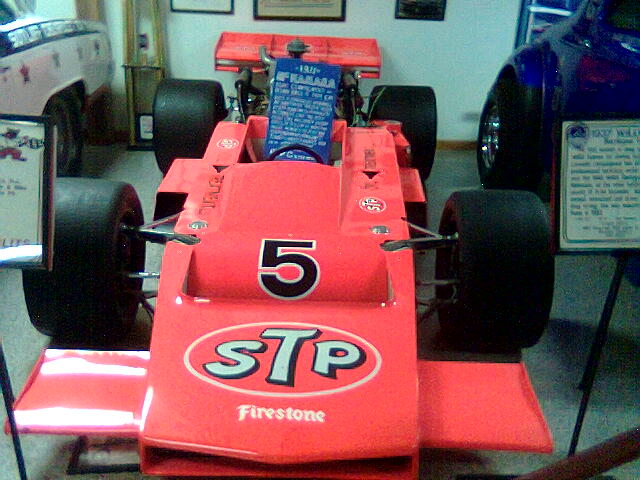 two red race cars on display in a museum