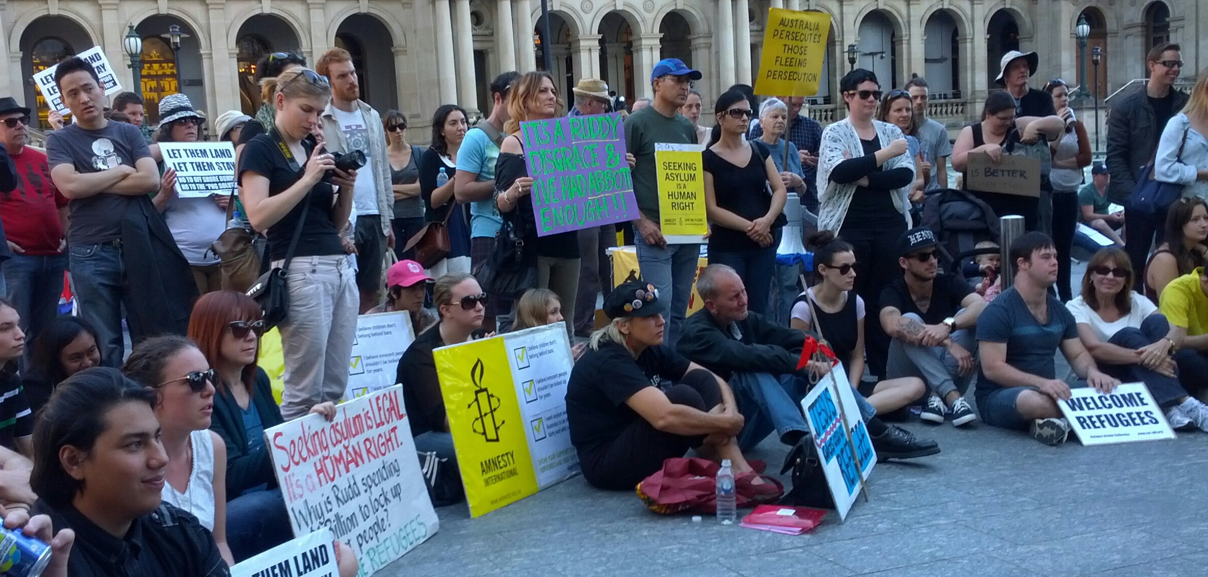 some protesters sitting in front of a building holding signs