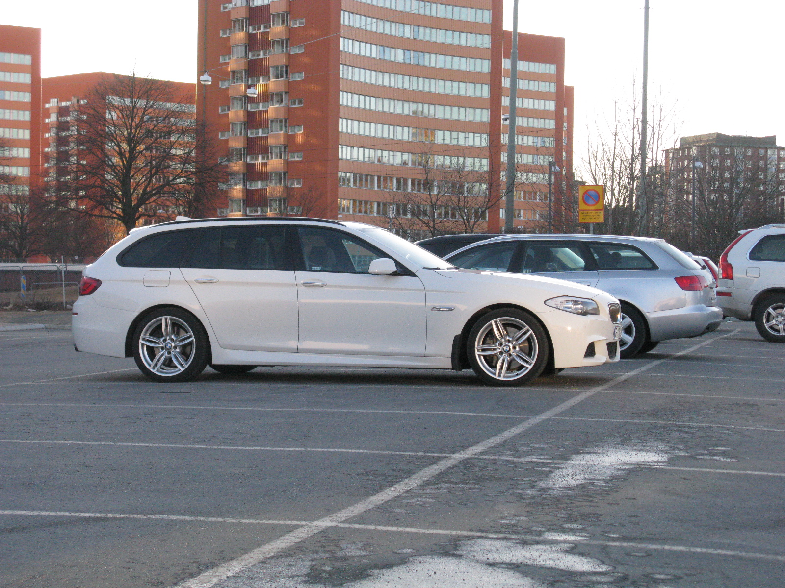 two cars parked in the parking lot with buildings in the background