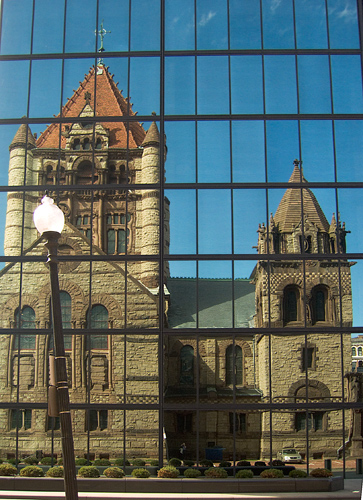 the large building is reflected on a glass window