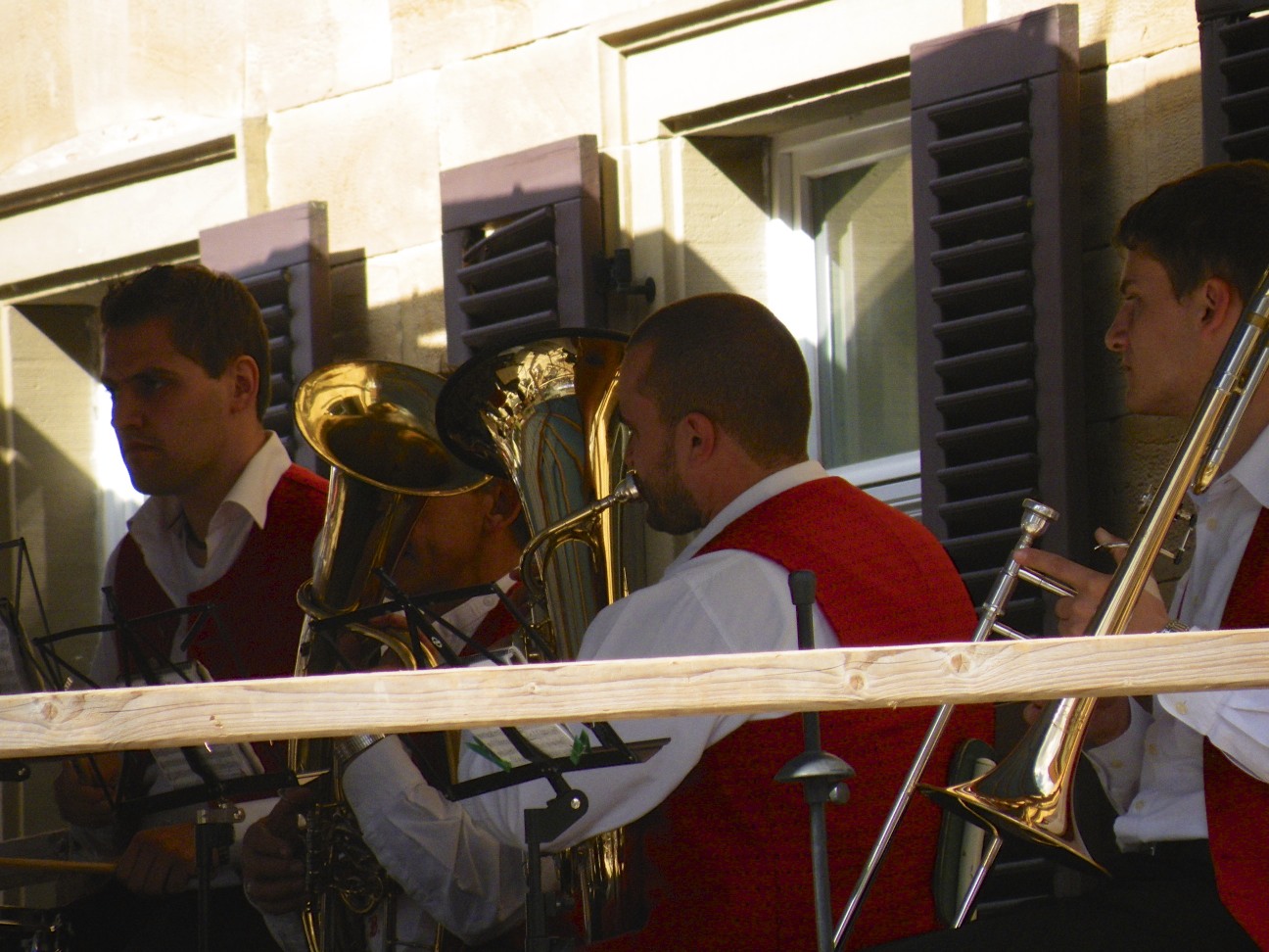 a group of men playing instruments near some windows