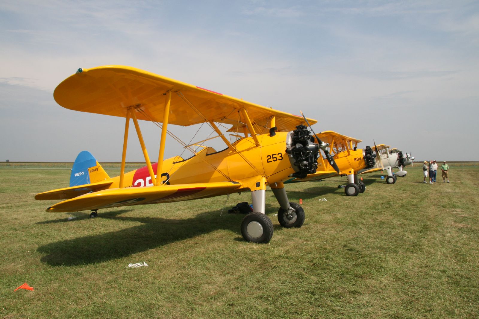 a row of yellow airplanes sit on a grass field