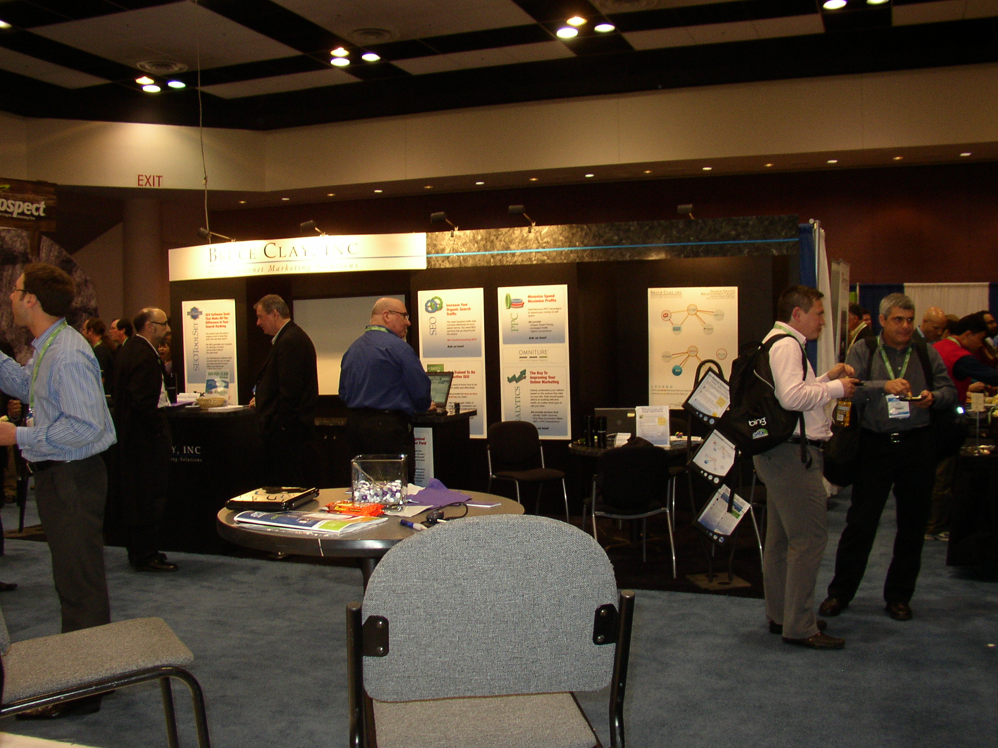 people are standing around a booth looking at posters