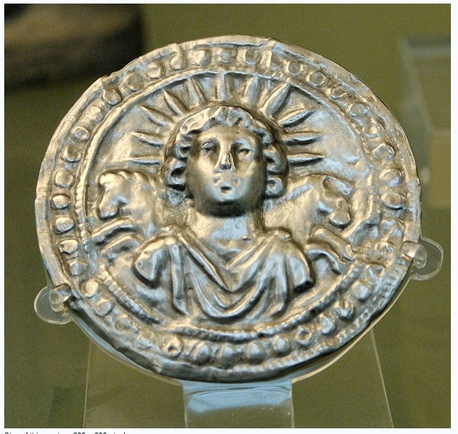 a silver object with a woman and a sun on it