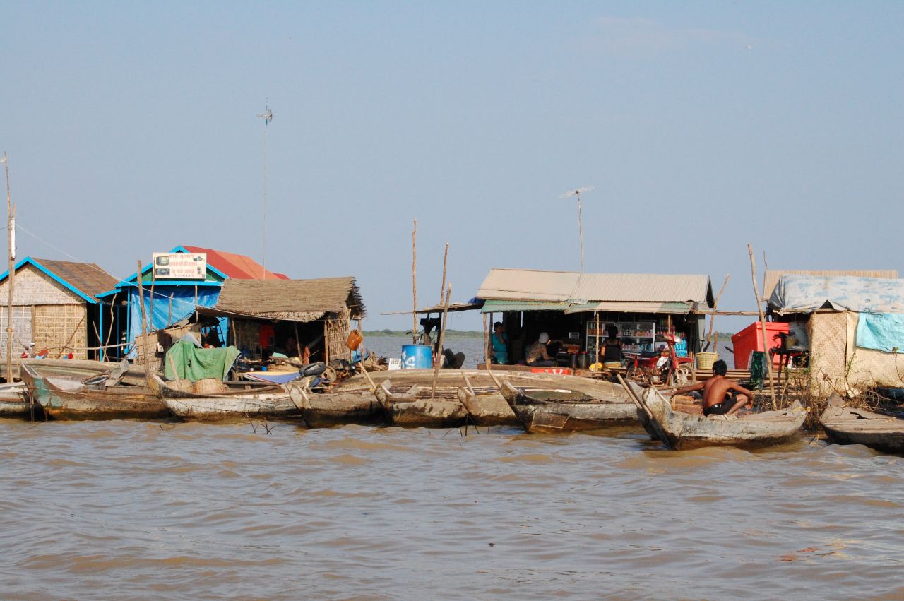 two wooden boats full of people near houses on the shore