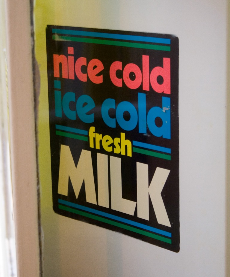 an ice cold fresh milk sign hangs on a wall