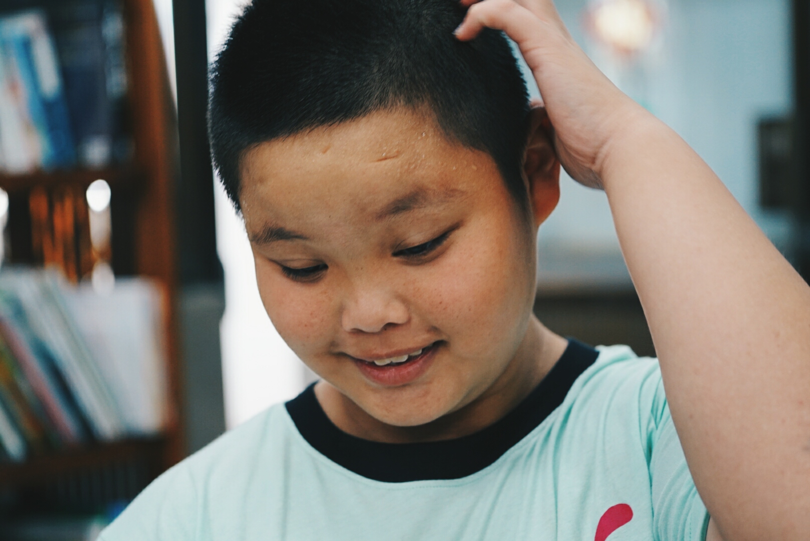 a boy is touching his hair while looking down