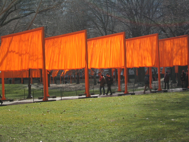 four large orange colored structures with people walking by