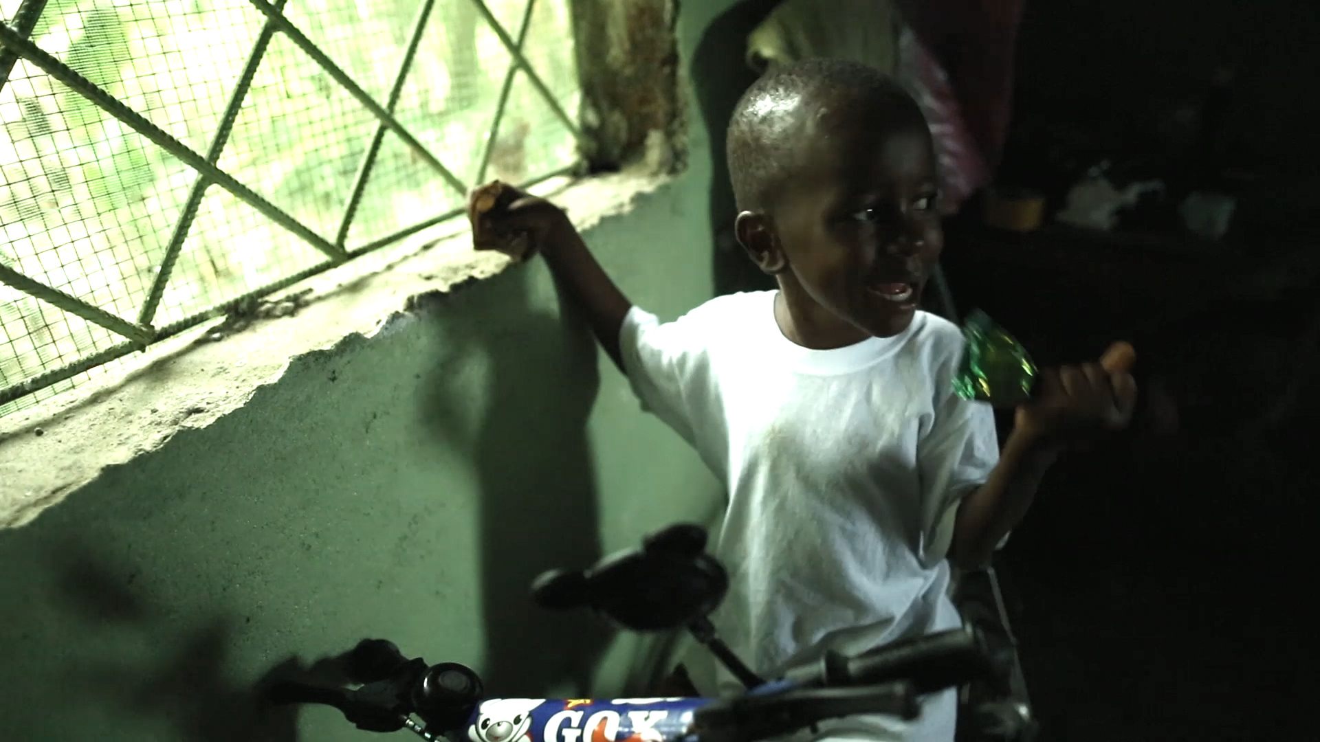 a small boy is standing with his bicycle