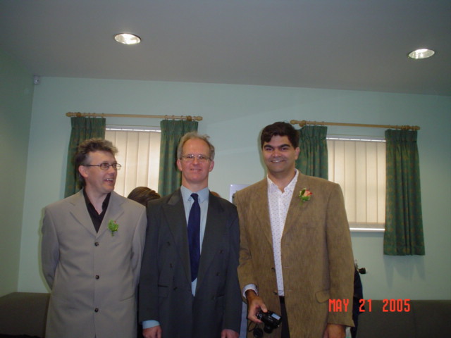 three men wearing jackets and smiling together in the corner