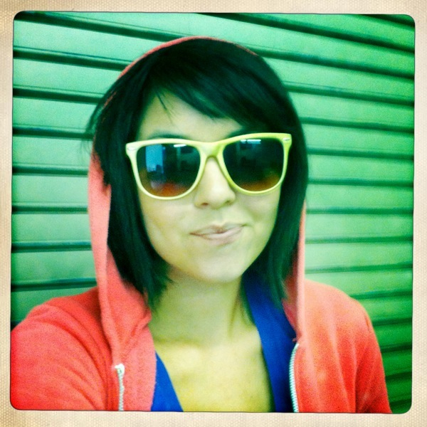 a woman in sunglasses with a red sweater and orange jacket