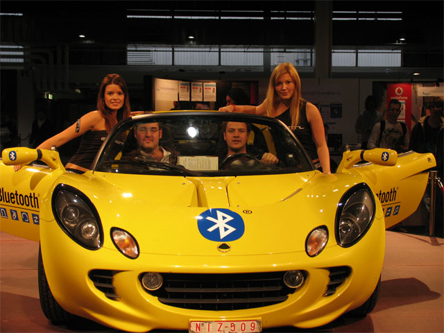 a man and two women posing with a yellow car